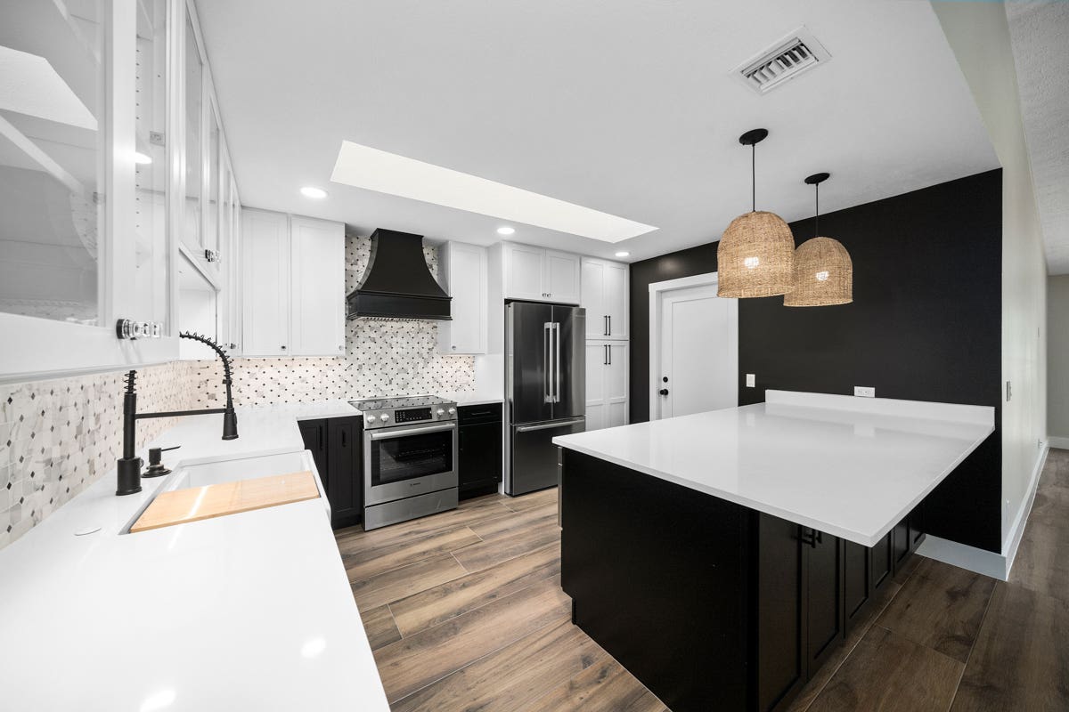 Large black shaker kitchen design and island with white glass wall cabinets, woven pendant lights and a black tapered wood range hood