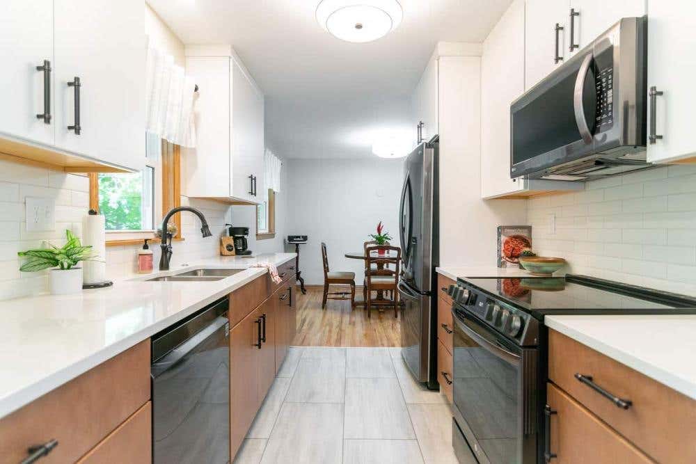 Two-tone galley kitchen with white slab wall door wall cabinets and wood slab door base cabinets