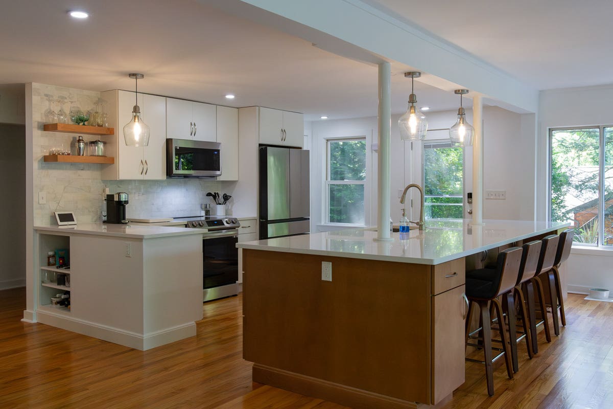 White slab door kitchen design with medium-tone wood island and microwave range hood White slab door kitchen design with medium-tone wood island and microwave range hood