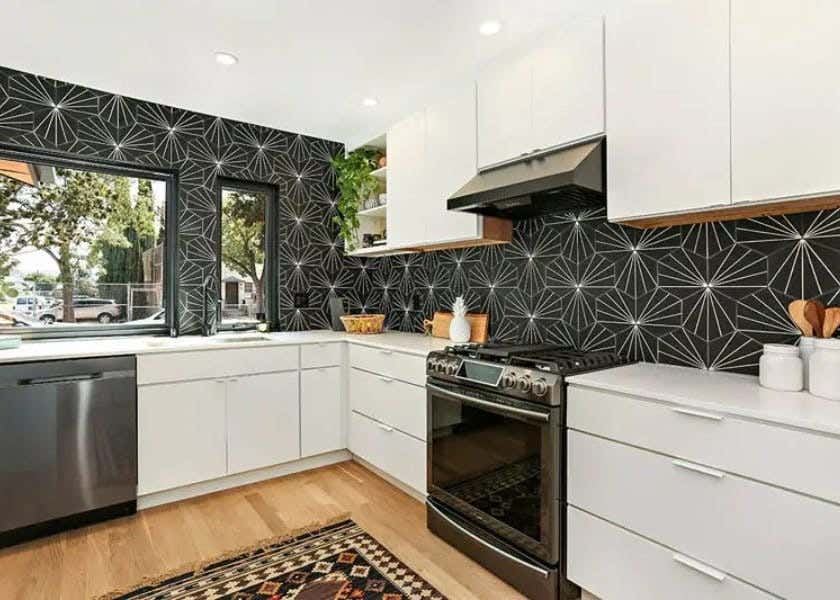 White slab kitchen cabinet design with brushed nickel finger pull cabinet hardware and a black and white starburst backsplash