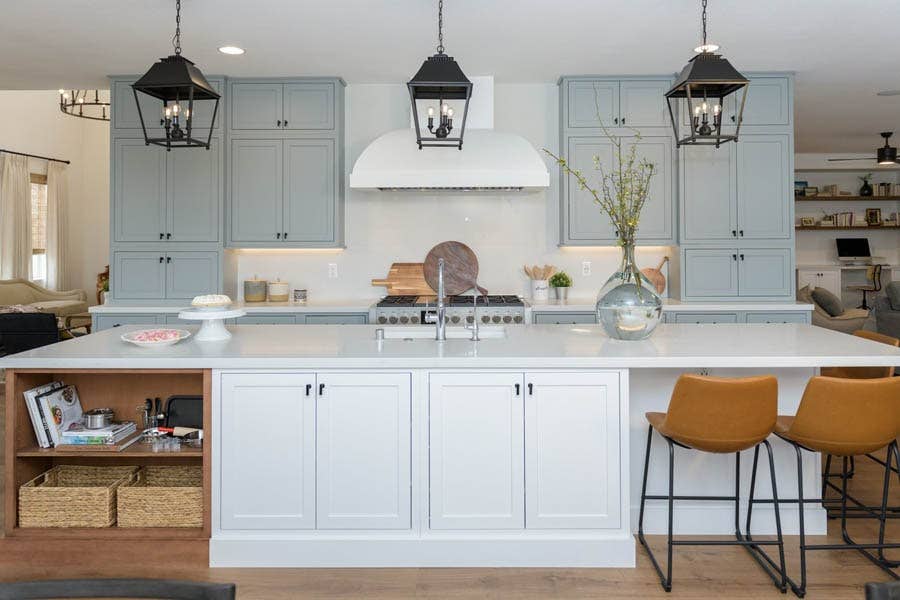 Light gray inset shaker kitchen cabinets with large white wood kitchen hood and black farmhouse pendants