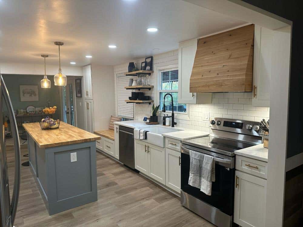 White shaker kitchen cabinets with shiplap wood kitchen hood a light gray shaker island cabinet and butcher block countertop