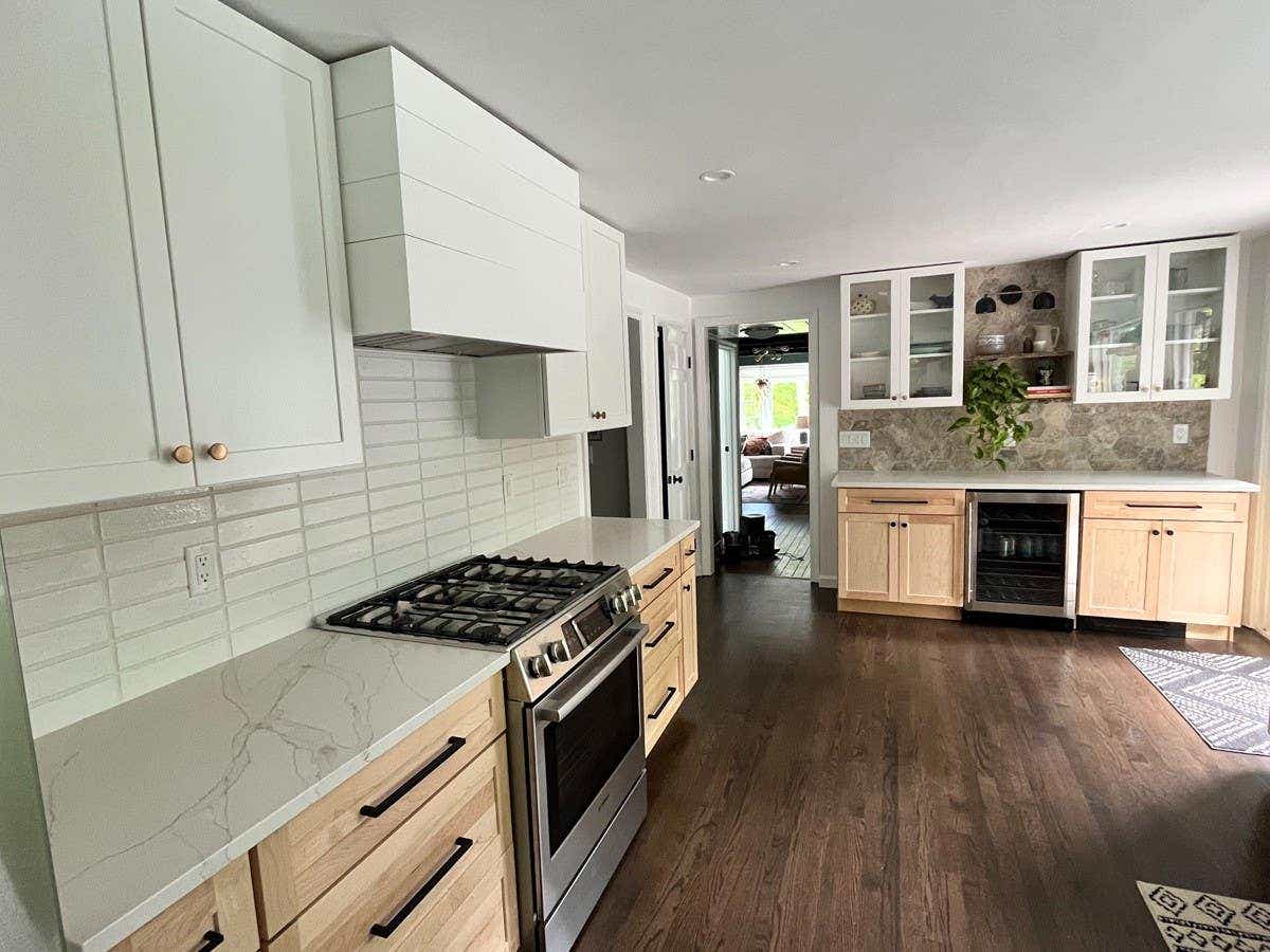 Boho-style shaker kitchen design with natural colored base cabinets and white wall cabinets with a shiplap white wood hood.