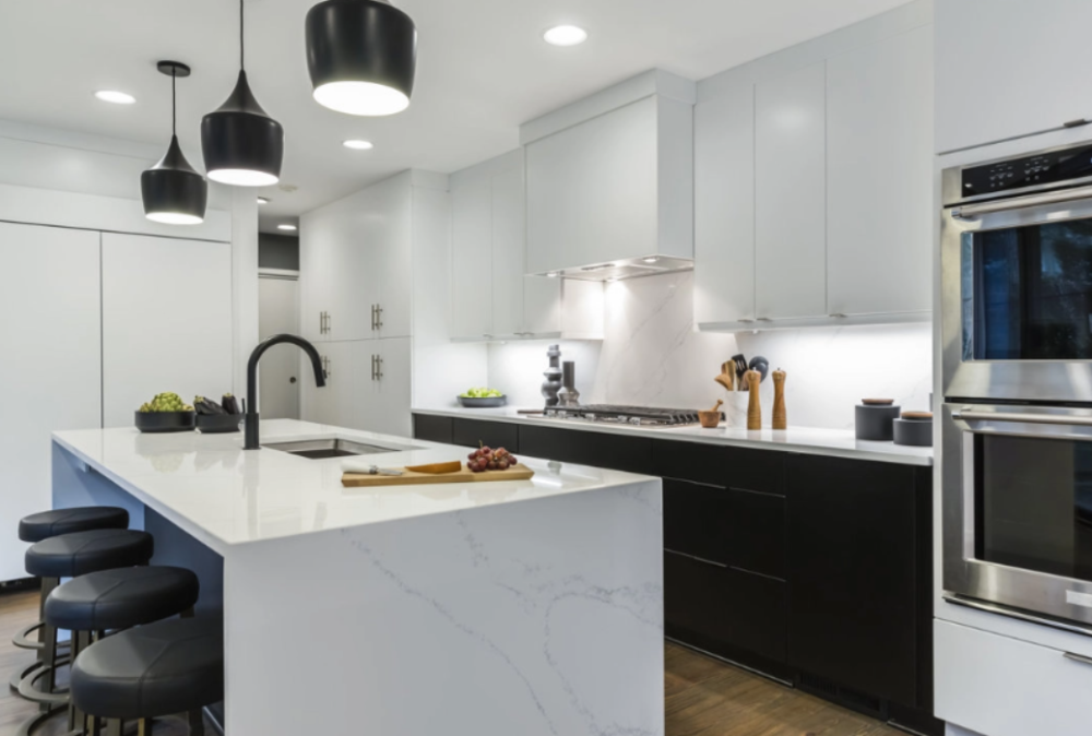 White quartz waterfall countertop with black slab cabinets