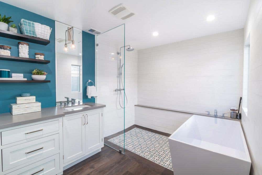 Modern white shaker bathroom cabinets with wood floating shelves next to glass shower and white free-standing tub Modern white shaker bathroom cabinets with wood floating shelves next to glass shower and white free-standing tub