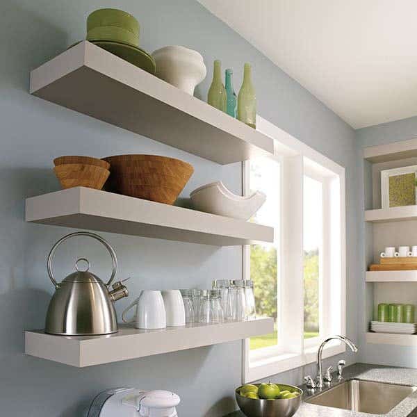 Three white wood floating shelves on baby blue kitchen walls