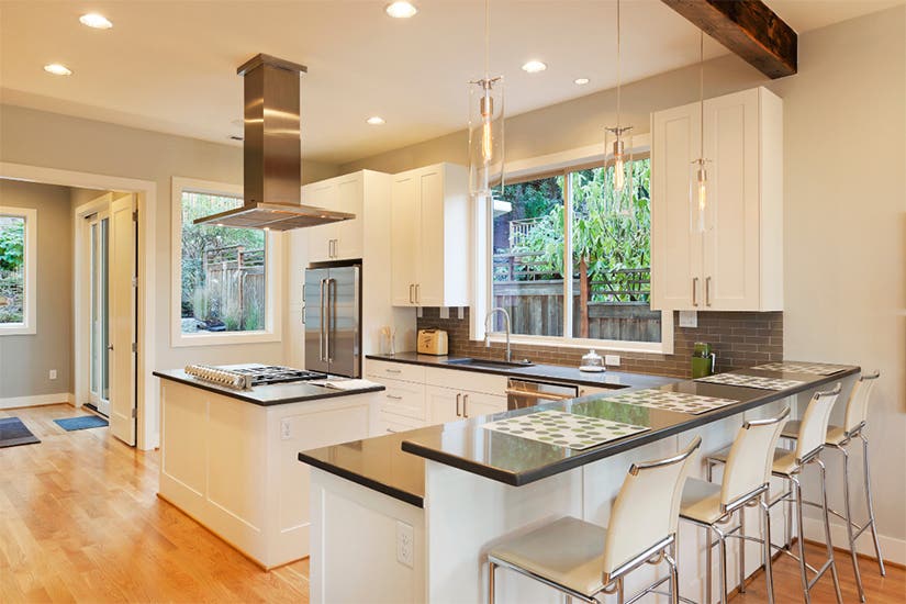 White L-shaped shaker kitchen design with a center island and stainless steel island range hood White L-shaped shaker kitchen design with a center island and stainless steel island range hood