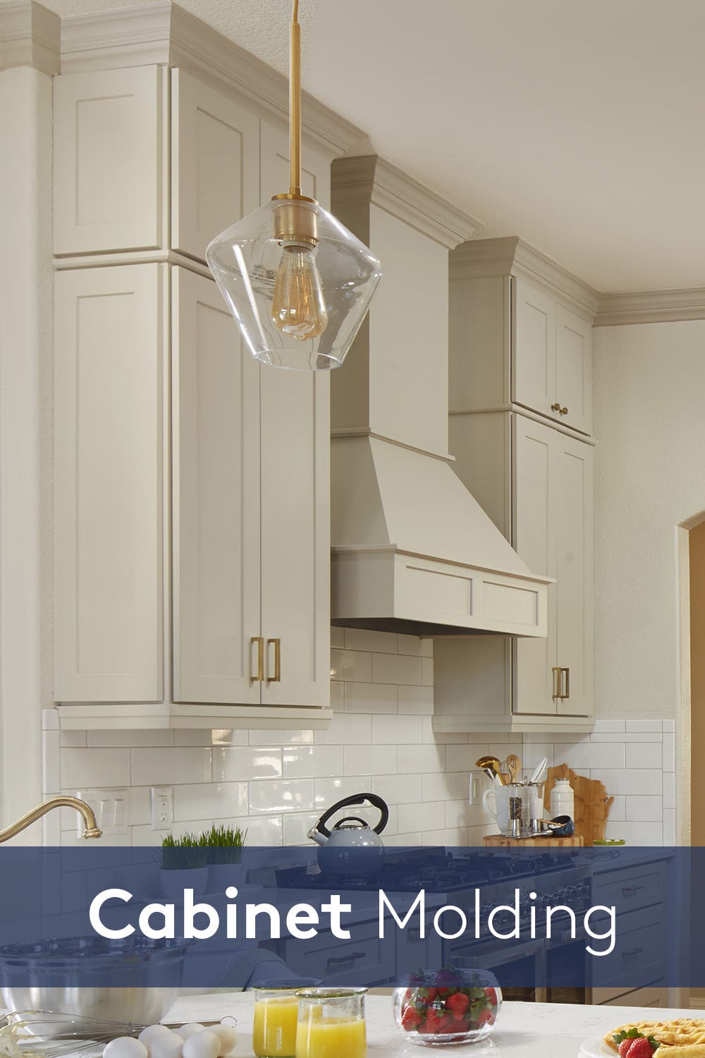 Stacked kitchen wall cabinets with gold hardware and accents in taupe paint color and matching wood hood in the center