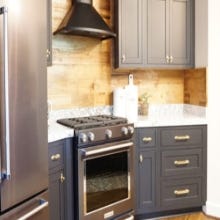 Black inset shaker kitchen cabinets with gold hardware, quartz countertops and slate colored appliances