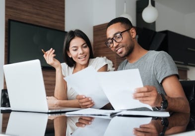 A couple with dark hair in sleek and contemporary room studying and writing on paperwork