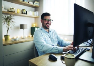 Man working on his desktop computer smiling