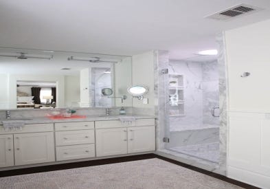 Beautiful makeover of master bath featuring CliqStudios Shaker White painted shaker style cabinets, frameless shower doors, and marble tile.