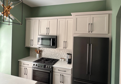 Light gray shaker kitchen cabinets with a small, decorative island with a built-in bookcase, green walls, and a neutral tile backsplash