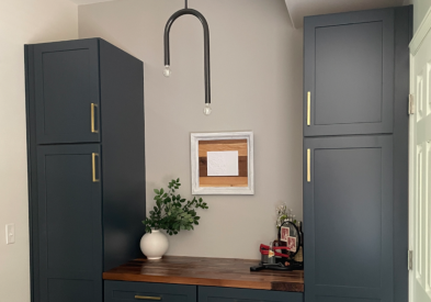 Dark indigo shaker cabinet bar with butcher block countertop flanked by tall pantries on either end