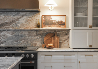 White shaker kitchen cabinets with stacked furniture wall cabinets, brass hardware, and a black chef's range