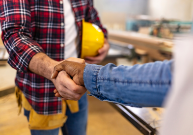 Contractor wearing a tool belt shaking hands with their client