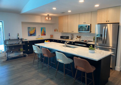 L-shaped kitchen design and island with black shaker base cabinets and natural maple wall cabinets.