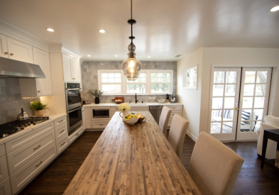 Decorative white shaker kitchen cabinets with white quartz countertops, gold hardware, and an indigo blue island with butcher block countertops