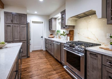 Light gray-brown stained kitchen cabinets with mullion doors, cream countertops, and a slab backsplash