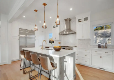 Stacked white inset cabinets with a gray stained kitchen island, white quartz countertops, and brown and gold accents