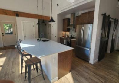 One-wall dark wood shaker kitchen design with a large island and white quartz countertops