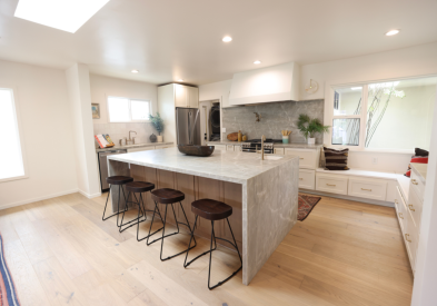 Modern and organic white shaker kitchen with warm wood island and gray quartz waterfall countertops