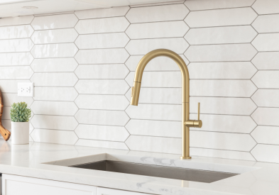 Shiny white picket fence tile with a gold gooseneck faucet