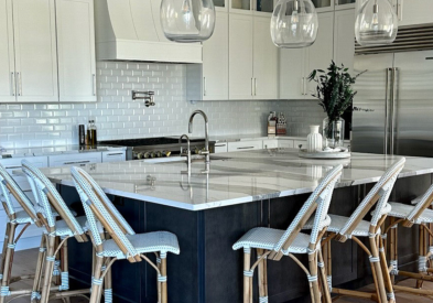 Light gray stacked shaker kitchen cabinets with dark gray island and luxurious white quartz countertops with veining