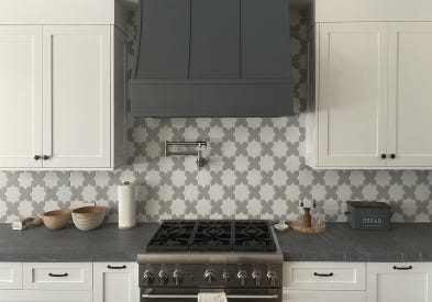 Sloped wood range hood with strapping in dark gray against taupe shaker cabinets