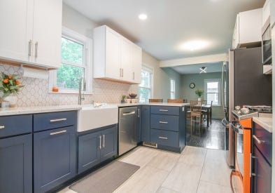 White and blue shaker kitchen cabinets with bright orange range and backsplash grout