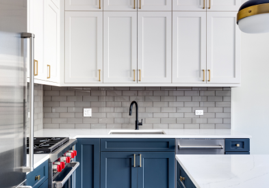 White and navy shaker kitchen cabinets with gold hardware and white quartz countertops