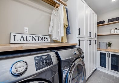 Shaker white laundry room sink cabinets with black hardware pulls and light butcher block countertops