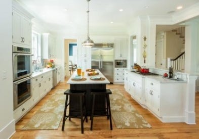 New kitchen is open to dining, living and stairs, with a long black center islands, white inset cabinets on the perimeter, and a professional cooktop in a built-in hearth.