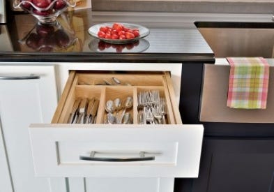 Smart storage solutions by CliqStudios keeps your kitchen organized with features such as this base cabinet built-in solid wood silverware tray shown here in Shaker cabinet style in painted White finish and paired with Shaker in painted black finis