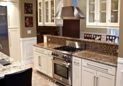 pro range and hood in peninsula built of white shaker cabinets with glass doors