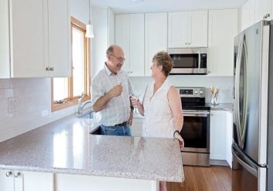 duluth minnesota couple in their new kitchen with white shaker cabinets, toasting with wine