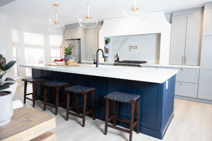 Light gray one-wall kitchen design in shaker cabinets with navy island and white quartz countertops