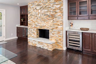 stone fireplace surround includes cherry cabinets, glass doors, open shelves and dry bar