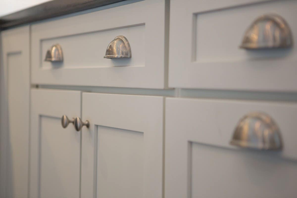 Cup pulls are often combined with a coordinating knob. The cup pull is used on the drawer, and the knob is used on all doors and upper cabinets.