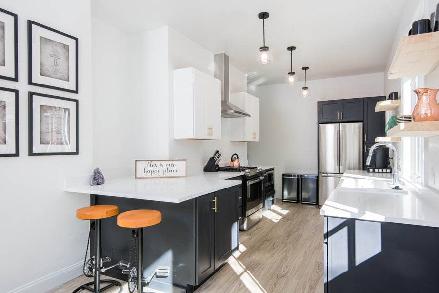 galley kitchen with black and white cabinets, a polished industrial style and small peninsula with seating for two