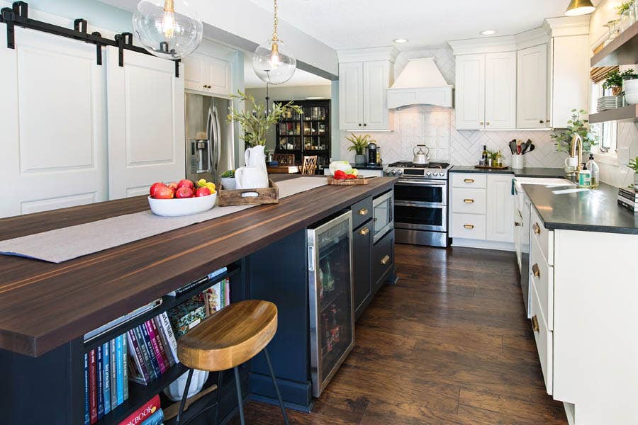 A black island with butcher block counter tops and a built in microwave, bookshelf, and cooler. A black island with butcher block counter tops and a built in microwave, bookshelf, and cooler.