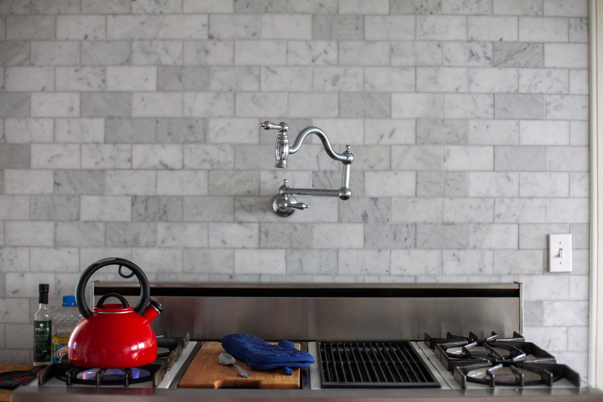 Traditional-style polished chrome pot filler on marble subway tile backsplash over a range Traditional-style polished chrome pot filler on marble subway tile backsplash over a range