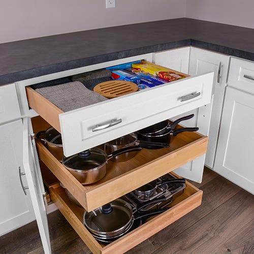 Two roll out trays and top drawer in a white shaker style base cabinet