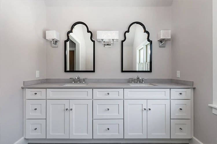 Double vanity with white Shaker cabinets, gray countertop with two black beveled mirrors above