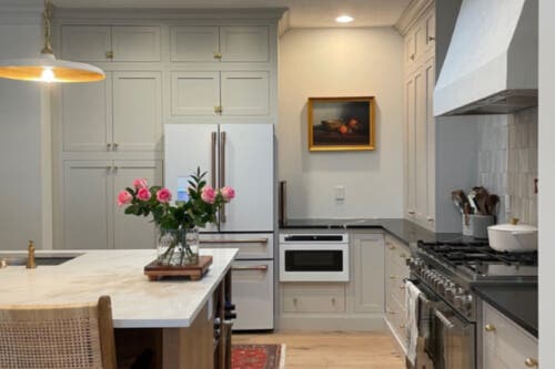 Brentwood Irish Creme and Biscotti kitchen cabinets Stacked creme kitchen cabinets in inset style with aged brass cabinet latches, soapstone countertops and a light wood island