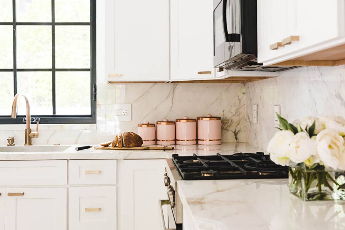 Bright painted white shaker kitchen with light slab marble backsplash with colorful accents