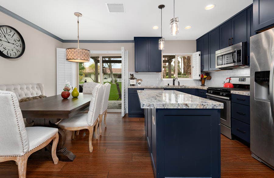 L-shaped blue shaker kitchen with white granite countertops next to large dining room table L-shaped blue shaker kitchen with white granite countertops next to large dining room table