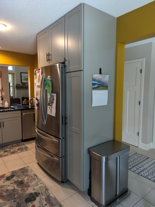 Gray shaker kitchen cabinets with black cabinet hardware and yellow walls