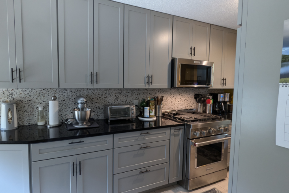 Gray shaker kitchen cabinets with black cabinet hardware and yellow walls