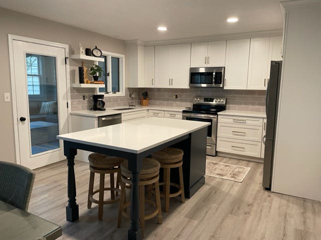 White shaker kitchen design with a dark indigo-blue island with furniture legs and seating White shaker kitchen design with a dark indigo-blue island with furniture legs and seating